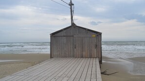 Un muelle de madera que conduce a una cabaña de playa de diseño sencillo, con vista al océano.