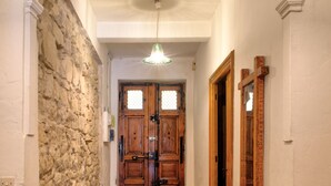 Un pasillo con pared de piedra, puerta de madera y un banco.