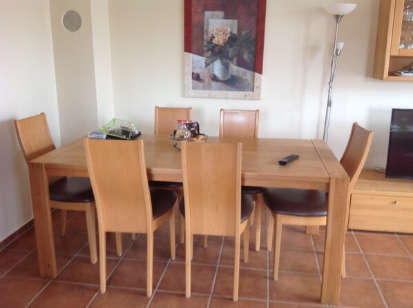 Un comedor con una mesa y sillas de madera, un cuadro en la pared y una lámpara.