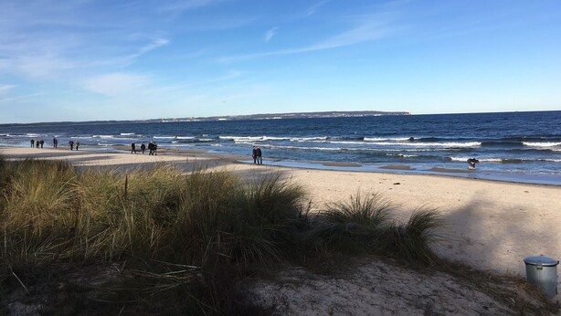 A beach with people walking along the shore, a clear sky, and the ocean in the background. - Comfortable holiday house for 7 persons with sauna, 110 sqm, in the south of Rügen (Zudar/Rügen)