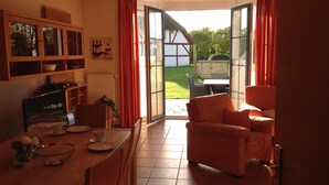 A cozy kitchen with a dining area, a large window, and a view of a garden. - Comfortable holiday house for 7 persons with sauna, 110 sqm, in the south of Rügen (Zudar/Rügen)