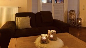 A living room with a dark-colored sofa, a wooden coffee table, and two decorative lamps. - Comfortable holiday house for 7 persons with sauna, 110 sqm, in the south of Rügen (Zudar/Rügen)
