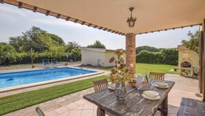 A patio with a pool, a dining table set with plates and glasses, and a brick pillar with a lantern. - Beautiful home in Orbetello -GR- (Orbetello -GR-)