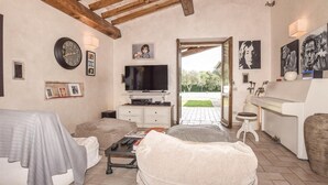 A cozy living room with a television, a clock, and framed photos on the wall. - Beautiful home in Orbetello -GR- (Orbetello -GR-)