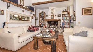 A cozy living room with two sofas, a coffee table, and a fireplace. There are bookshelves filled with books and decorative items on the walls. - Beautiful home in Orbetello -GR- (Orbetello -GR-)