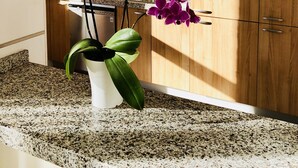 A kitchen with wooden cabinets, a granite countertop, and a potted orchid plant. - Luxury penthouse with stunning views of the sea and golf course (Mijas)
