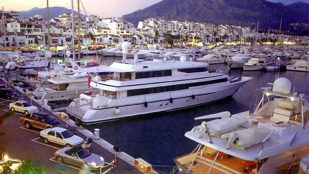 A marina with multiple yachts docked, surrounded by residential buildings and a mountainous backdrop. - Luxury penthouse with stunning views of the sea and golf course (Mijas)