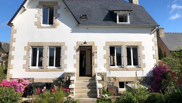 Une maison à deux étages avec un toit à pignon, une entrée sur la façade avec des marches et un petit porche.
