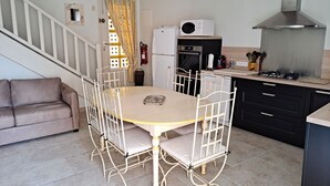Une cuisine de taille réduite comprenant une table à manger, des chaises, une cuisinière, un four et un réfrigérateur.