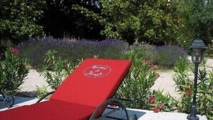 Un fauteuil rouge, orné d’un logo, placé à l’extérieur, avec un jardin et un lampadaire en arrière-plan.