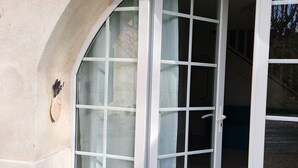 Une entrée d’immeuble avec une arche incurvée, une porte en verre dotée d’un cadre blanc et un petit élément décoratif sur le mur.