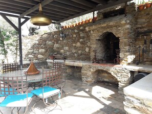 An outdoor patio with stone walls, a metal grill, and blue chairs. - A FEW STEPS FROM THE SEA, MAS DES PORTALS CRIQUES MAGNIFICENT VIEW, (COLLIOURE)