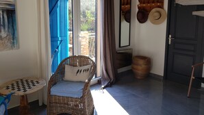 A room with a wicker chair, a checkered table, a blue door, a mirror, and a door with hats hanging on it. - A FEW STEPS FROM THE SEA, MAS DES PORTALS CRIQUES MAGNIFICENT VIEW, (COLLIOURE)
