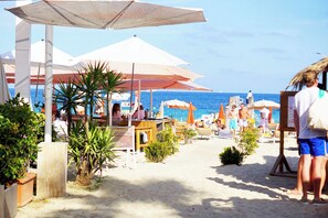 A beachside café with outdoor seating and umbrellas, overlooking the sea. - Exceptional cottage with private garden, 100m from Tahiti beach &  St Tropez 2mn (Ramatuelle)