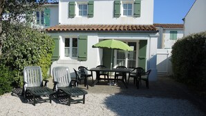 Uma área de pátio com móveis de exterior, uma mesa e um guarda-sol verde.