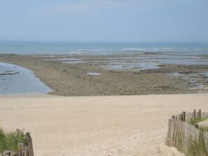 Ein sandiger Strand mit einer Holzzaun und einer felsigen Küste.