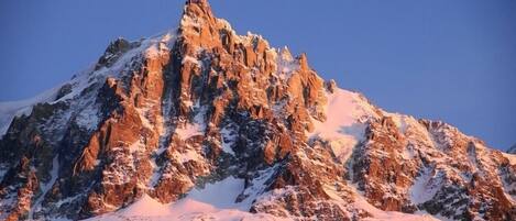 A snow-covered mountain peak with rugged terrain and a clear sky.