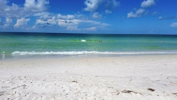 A beach with white sand and clear turquoise water.