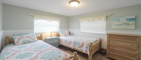 A bedroom with two beds, a dresser, a nightstand, and a ceiling light.