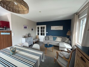 A living room with a sofa, a dining table, and a kitchen area with a counter and cabinets.