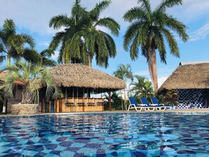 A swimming pool with lounge chairs and thatched-roof structures. - A Relaxing Retreat in the Punta Chame Area. Your Perfect Escape Awaits! (Chame)