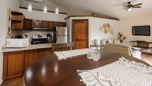 Une cuisine moderne avec des meubles en bois, une table à manger agrémentée de sets de table en macramé et un ventilateur de plafond.