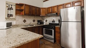 Une cuisine avec des meubles en bois, un réfrigérateur en acier inoxydable, une cuisinière et un four à micro-ondes.