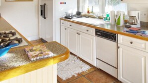 A kitchen with white cabinets, a white refrigerator, a sink, and a coffee maker. - Dunes, Daisies, Surf, Sand, Sunsets...Historic BUTLERHOUSE,  Pass-a-Grille (St. Pete  Beach)