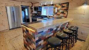 A modern kitchen with a wooden island, bar stools, stainless steel appliances, and a colorful backsplash. - Sight distance of Lake Superior Beach, Autrain River, Close to Pictured Rocks (Au Train)