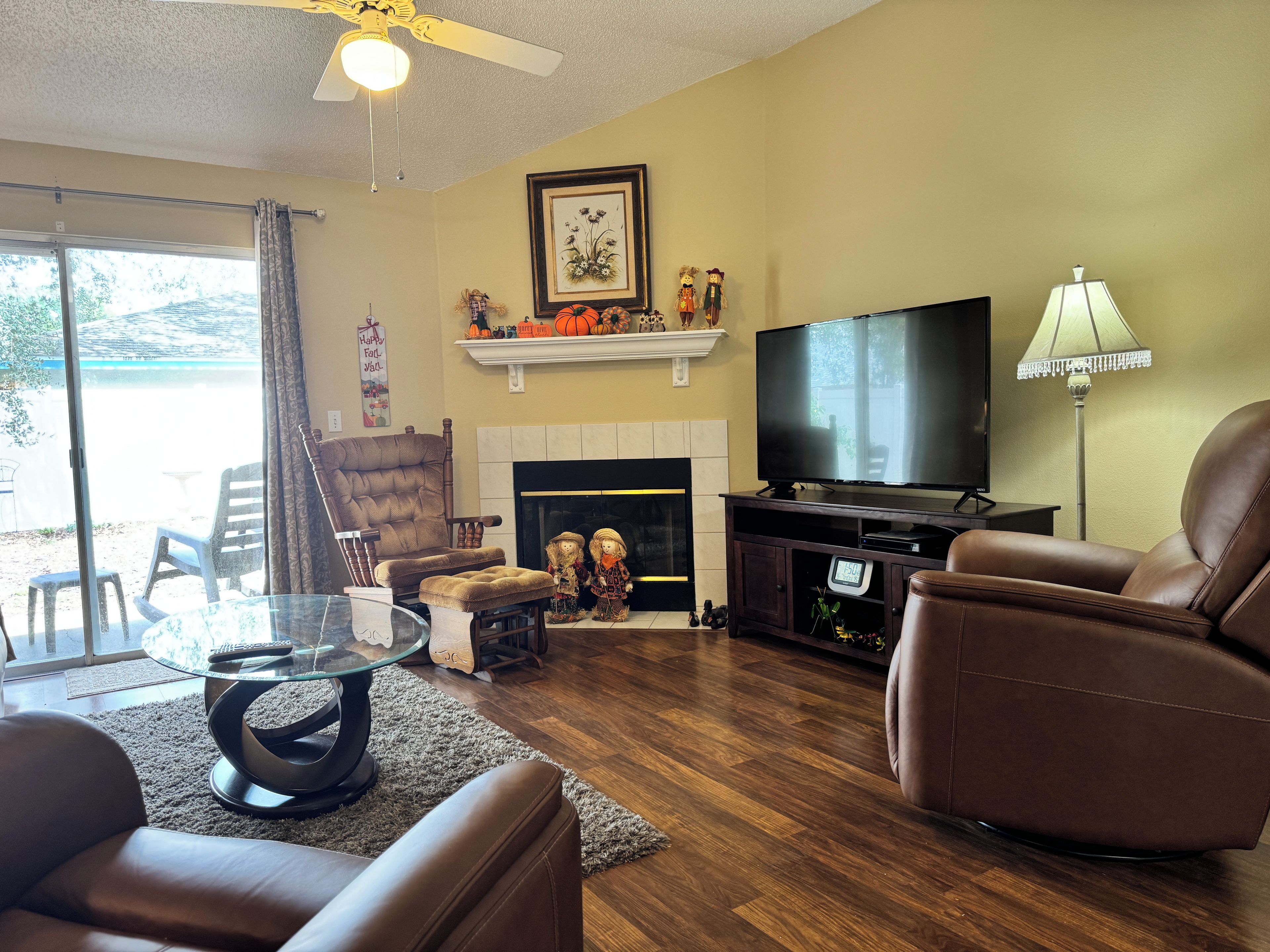 A living room with a fireplace, television, and leather chairs.
