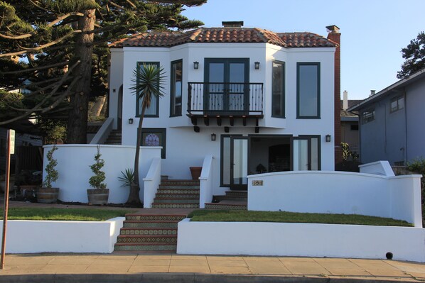 A two-story house with a balcony, a staircase with patterned tiles, and a well-maintained lawn.