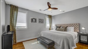 Une chambre à coucher avec un lit, un ventilateur de plafond, une table de chevet et un bureau.