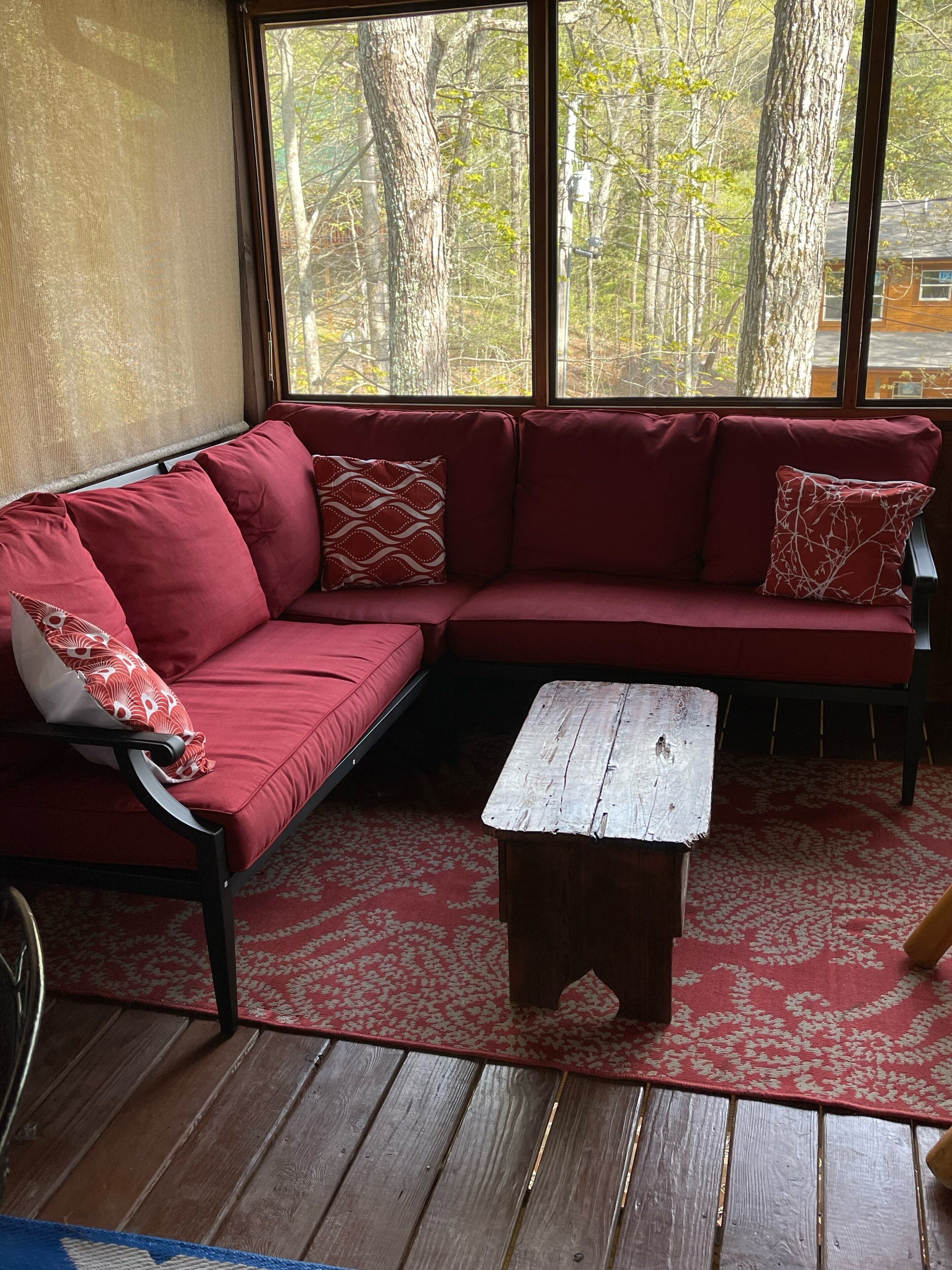 Un divano componibile rosso con cuscini decorati, un tavolino da caffè in legno e un tappeto rosso con motivo.