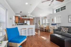 A spacious living area with a sofa, a dining table with chairs, a kitchen area, and a ceiling fan. - Rockport at CrossTimbers Marina (Sperry)