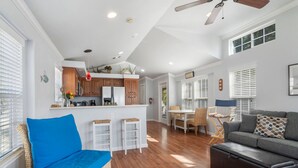 Un grand espace de vie comprenant un canapé, une table à manger avec des chaises, un coin cuisine et un ventilateur de plafond.