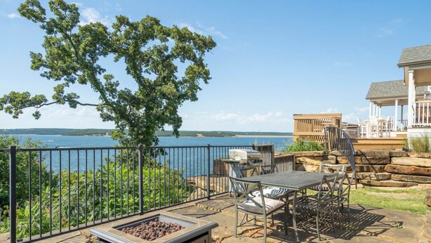 Une terrasse avec des meubles d’extérieur, un foyer et une vue sur un lac.