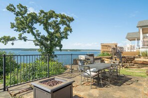 Un patio con mobiliario exterior, una fogata y vistas a un lago.