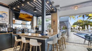 Eine moderne Bar mit Granitplatte, Barhocker und Blick auf den Pool.