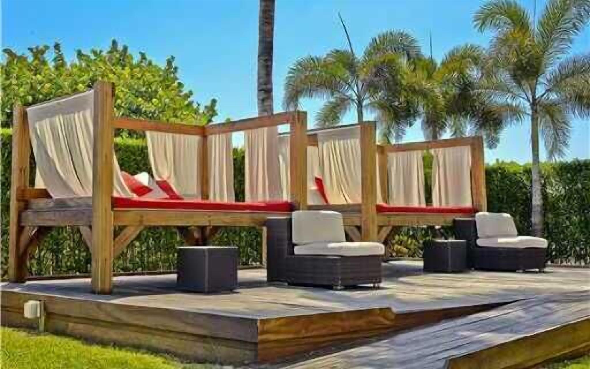 Une terrasse dotée de deux chaises longues en bois, chacune agrémentée d’un coussin et d’une petite table.