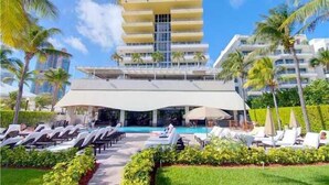 Ein Hotel mit modernem Design, das einen Poolbereich mit Liegestühlen und eine überdachte Sitzgelegenheit bietet.