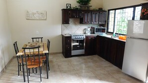 A kitchen with a dining table, chairs, a stove, oven, microwave, cabinets, and a refrigerator.