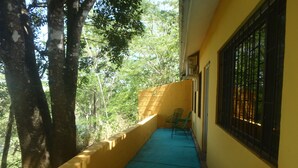 A narrow balcony with a blue floor, a yellow wall, and a metal window grille.