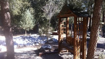 Un pabellón de madera en un área boscosa con un sendero de piedra y rocas.