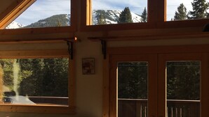 Habitación con amplios ventanales que ofrecen vistas a montañas nevadas y árboles.