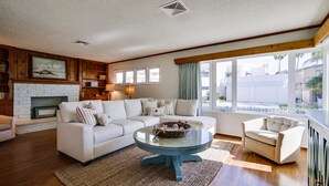 Un salon moderne avec un canapé d’angle, une table basse ronde et une cheminée.