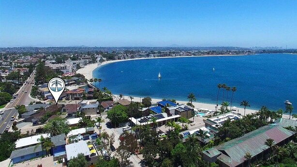 Une ville côtière avec une plage, des bâtiments et un ciel bleu dégagé.