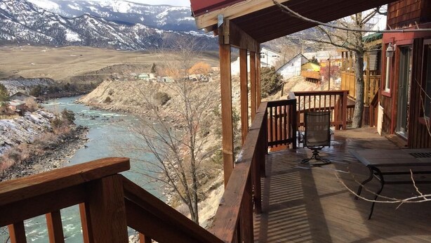 A wooden deck with a view of a river and mountains.
