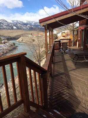 A wooden deck with a view of a river and mountains. - Grizzly Den -  Above the River! Yellowstone mountain views and Air Conditioning! (Gardiner)