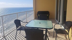 Un balcon avec une table et des chaises, une vue sur l’océan et une porte-fenêtre coulissante.