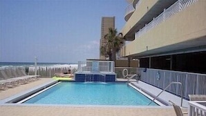 Une piscine dotée d’une terrasse ensoleillée, de chaises longues et offrant une vue sur l’océan.